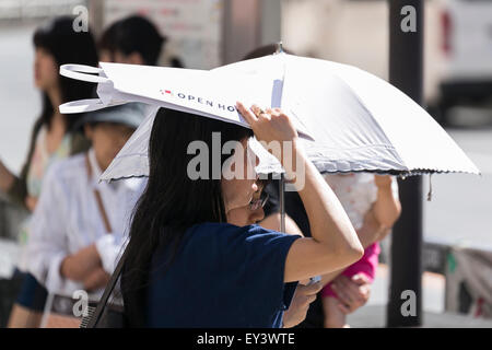 Tokyo, Japan. 21st July, 2015. Pedestrians hold parasols to get some shade in the hot weather in Shinjuku district on July 21, 2015, Tokyo, Japan. The Japan Meteorological Agency announced on Sunday that they believe the annual rainy season is over 2 days earlier than usual in the Tokyo region. Credit:  Rodrigo Reyes Marin/AFLO/Alamy Live News Stock Photo