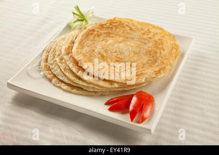 Plain paratha puri served with freshly sliced tomato and cucumber Stock Photo