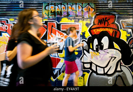 People walking past the graffiti on the wall in the Leake Street tunnel, Waterloo, London England UK Stock Photo