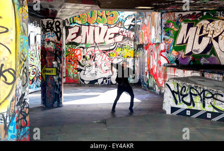 A street entertainer practicing his steps surrounded by graffiti, The skate park, South Bank, London UK Stock Photo