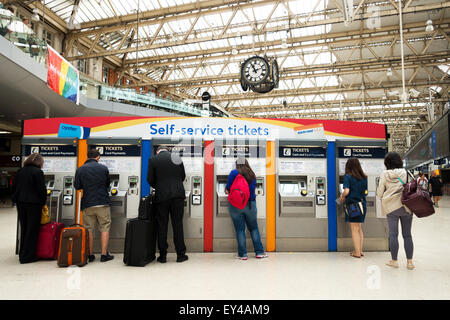 People buying rail tickets from a self service ticket booth, Waterloo railway station London UK Stock Photo