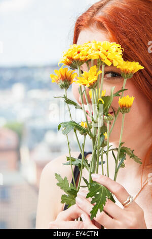 Close up Thoughtful Pretty Young Woman Holding Yellow Flowers, Looking Outside While Leaning on Glass Window. Stock Photo