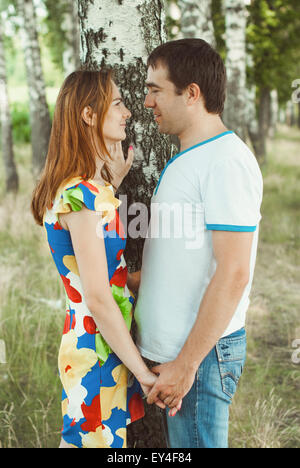 Young couple holding hands in the park among birches. Stock Photo