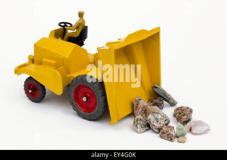 Vintage toy tipper truck tipping stones from bucket. Isolated on a white background. Stock Photo