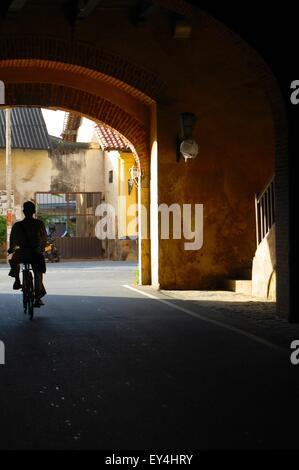 A silhouette of a man riding a bicycle through the old Portuguese Gate of the fortress walls in Galle, Sri Lanka Stock Photo