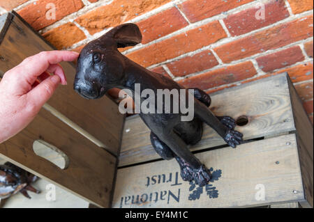 Black painted brass model of an Hare sitting on a National Trust wooden box. Stock Photo