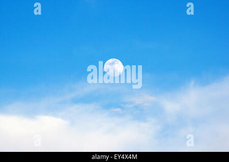 Moon rising above the clouds during a spring afternoon Stock Photo