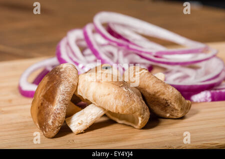Mushrooms and sliced red onions on cutting board Stock Photo