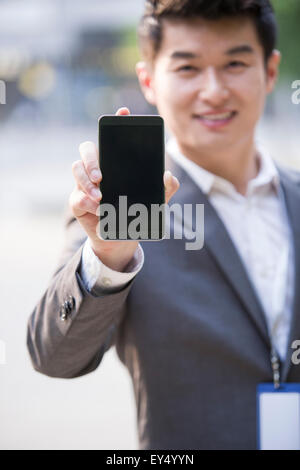 Young businessman showing smart phone Stock Photo