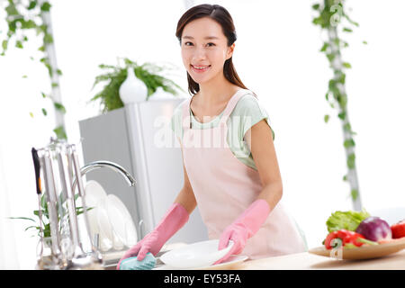 Young woman washing dishes in kitchen Stock Photo