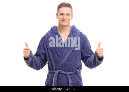 Young man in a blue bathrobe giving thumbs up and looking at the camera isolated on white background Stock Photo