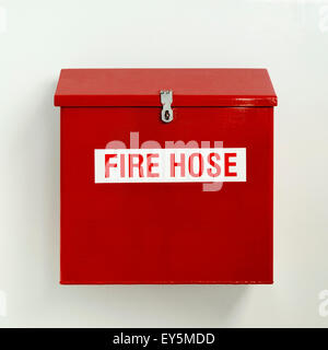 Fire hose box in bright red hung on white wall Stock Photo