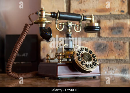 An antique analog telephone set with black box base and golden ringer, and handset Stock Photo