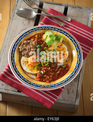 Huevos rancheros. Fried eggs on tortillas with tomato chilli sauce and refried beans Stock Photo