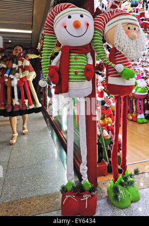 Yiwu, China's Zhejiang Province. 19th July, 2015. A businesswoman carries newly designed extensible Santa Claus dolls at Yiwu International Trading Mall, east China's Zhejiang Province, July 19, 2015. Known as the worldwide largest trading hub of Christmas commodity, Yiwu has come to its peak season of production and sale since July. © Tan Jin/Xinhua/Alamy Live News Stock Photo