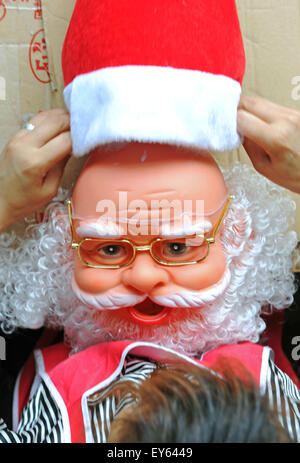 Yiwu, China's Zhejiang Province. 19th July, 2015. A worker puts on hat for a Santa Claus doll in Yiwu, east China's Zhejiang Province, July 19, 2015. Known as the worldwide largest trading hub of Christmas commodity, Yiwu has come to its peak season of production and sale since July. © Tan Jin/Xinhua/Alamy Live News Stock Photo