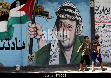 Rafah, Gaza Strip, Palestinian Territory. 22nd July, 2015. Palestinian children walk past a mural depicts former Palestinian leader Yasser Arafat, in Rafah in the southern Gaza Strip, July 22, 2015. French public prosecution said on Tuesday that France requires no further investigation into murder allegations of late PLO leader Yasser Arafat. Arafat died aged 75 at French military hospital in November 2004, weeks after falling ill at his compound in the West Bank city of Ramallah (Credit Image: © Abed Rahim Khatib/APA Images via ZUMA Wire) Stock Photo