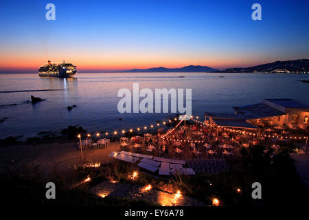 A seaside restaurant and a cruise ship, somewhere between 'Little Venice' and the windmills in the Hora of Mykonos, Greece Stock Photo