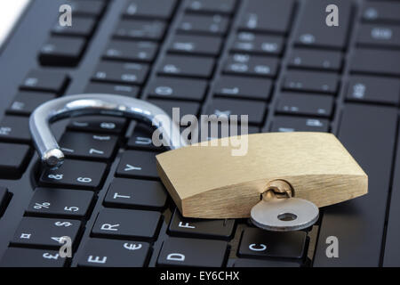 Close-up of a key in an unlocked padlock on a computer keyboard. Concept photo of Internet and computer security. Stock Photo