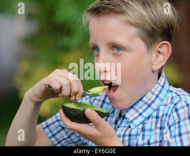 A child eating an avocado with a spoon as a healthy snack Stock Photo