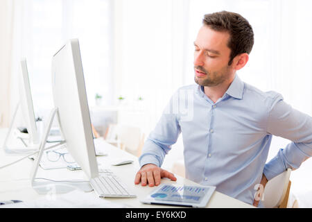 View of a Young attractive man got a back pain at the office Stock Photo