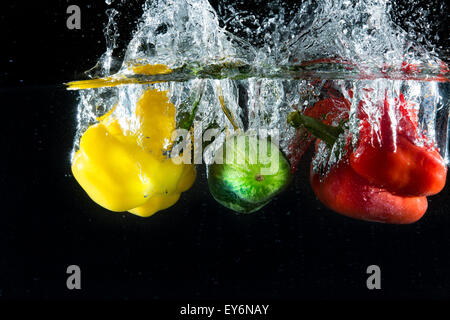 Vegetables in different colors, yellow and red, thrown into water to create splash effect Stock Photo