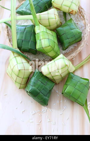 Freshly woven ketupat casings on wooden board Stock Photo