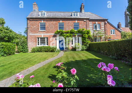 UK prime real estate: Pretty red brick town house property with pink roses in the garden, Cerne Abbas, a village in Dorset, SW England, in summer Stock Photo