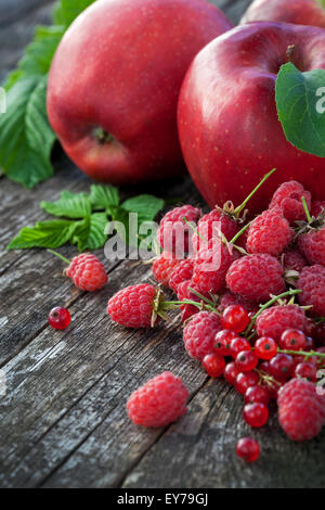 Redcurrant, raspberry and red apples on old wooden table, mix of red ...