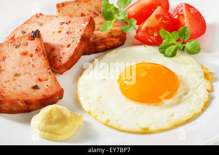 Pan-fried meatloaf with sunny side up fried egg and mustard Stock Photo