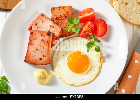 Pan-fried meatloaf with sunny side up fried egg and mustard Stock Photo