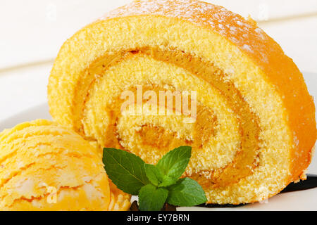 Slice of Swiss roll with yellow ice cream Stock Photo