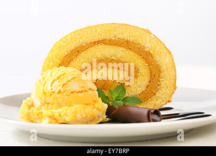 Slice of Swiss roll with yellow ice cream and chocolate sauce Stock Photo