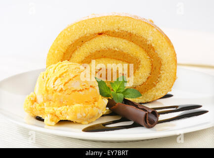 Slice of Swiss roll with yellow ice cream and chocolate sauce Stock Photo