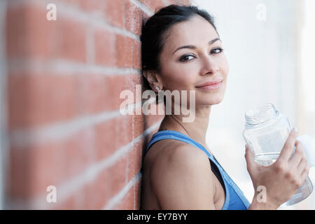 Portrait of young woman by brick wall Stock Photo