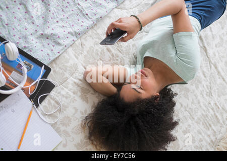 Teenage girl (16-17) texting in bedroom Stock Photo