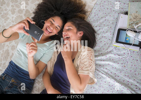 Teenage girls (14-15, 16-17) texting in bedroom Stock Photo