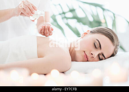 Therapist putting massaging oil on young woman in spa Stock Photo