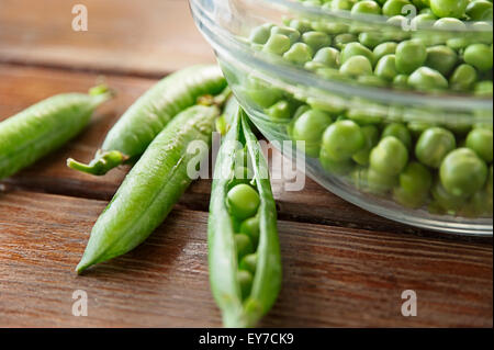 Pea pods and glass bowl full of peas Stock Photo