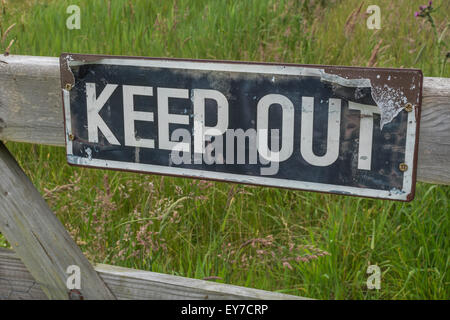 Warning sign - Keep Out - on gate.  Metaphor for 'obey', closed meeting, not invited, keep away, none of your business, trespassing. Stock Photo