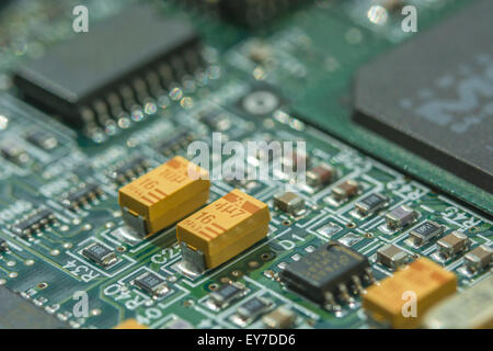 Macro-photo of printed circuit board (PCB) showing yellow tantalum (a rare earth) oxide capacitors. Circuit close up macro, detail of a circuit board. Stock Photo