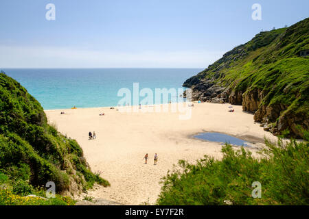 People sunbathing on a beautiful summer day on a sandy beach in the cove at Porthcurno beach, Cornwall, UK Stock Photo
