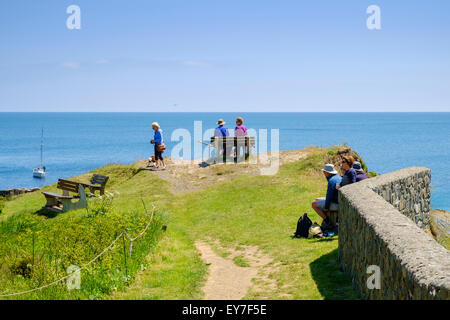 Tourists looking out to sea on the harbor walls at Cadgwith, Lizard Peninsula, Cornwall, England, UK Stock Photo