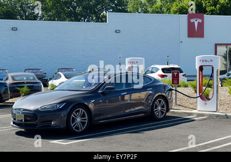 Electric car charging station with a Tesla sedan plugged in. Tesla dealership, Paramus, NJ Stock Photo