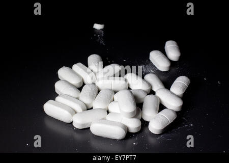 dusty white pills on a black table Stock Photo