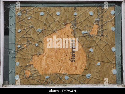 A smashed window repaired with a wooden panel Stock Photo