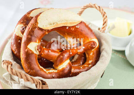 Delicious german pretzels with butter on sunlighted table. For breakfast, snack or picnic. Selective focus. Stock Photo