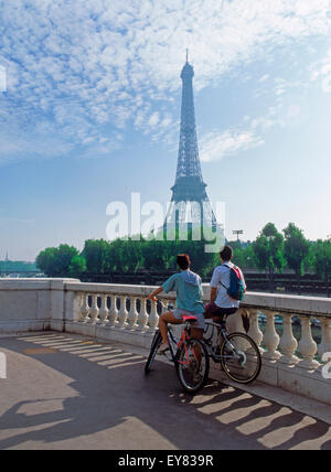 Couple sitting on bikes looking toward Eiffel Tower in Paris Stock Photo
