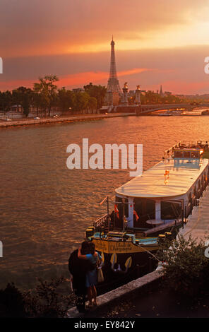 Couple near houseboats on River Seine in Paris at sunset with Eiffel Tower Stock Photo