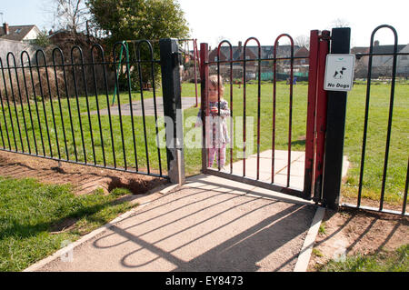 Toddler opening playground gate Stock Photo